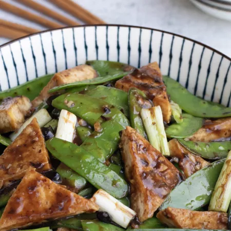 bow of tofu triangles and snow peas with scallions and garlic