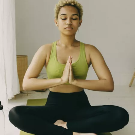 woman sitting crisscross with prayer hands as a yoga pose