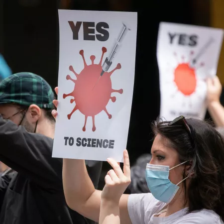 A group of people holding pro-science signs and wearing masks