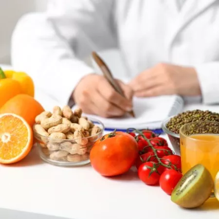 Young female nutritionist with healthy food writing diet plan in office, closeup
