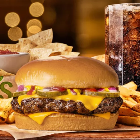 Chilis Big QP burger surrounded by fries with chips and salsa and large soda