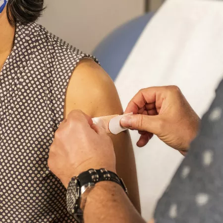 A band-aid being placed on a woman's arm after receiving a vaccine.