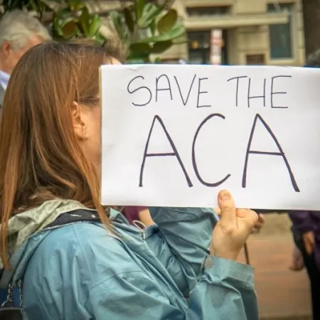 Rally in Support of the Affordable Care Act, at The White House, Washington, DC USA, carrying a sign that reads "SAVE THE ACA"