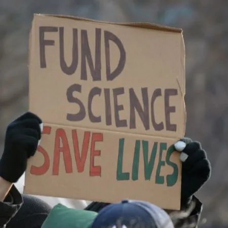 A protest sign reads "FUND SCIENCE SAVE LIVES"