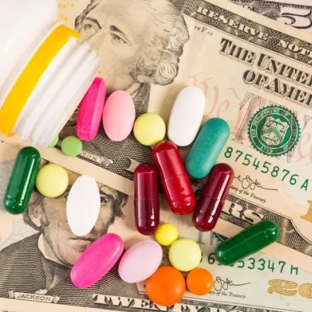 Money with a handful of supplements and tablets on top.