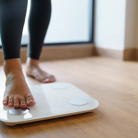 person stepping on a scale on wood floor