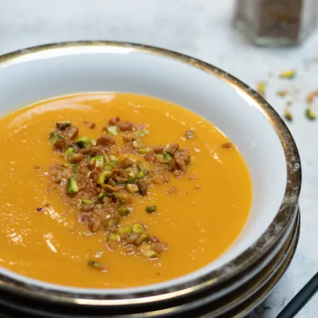 white bowl filled with butter nut soup and dukkah