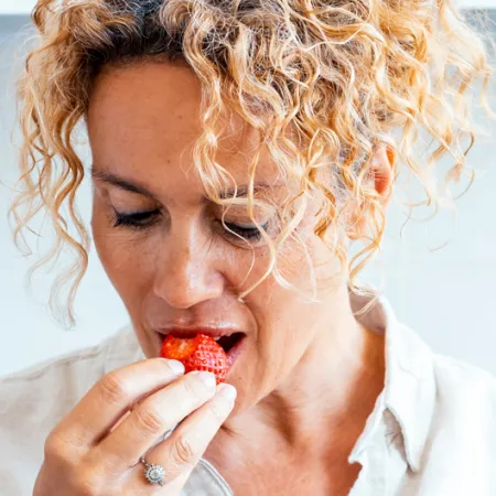 Woman taking a bite of a red berry