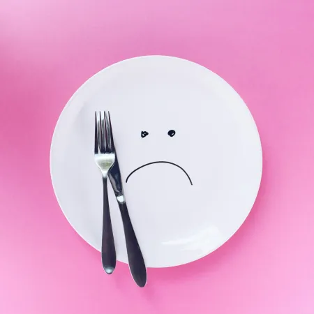An empty plate with a sad face drawn on with marker.
