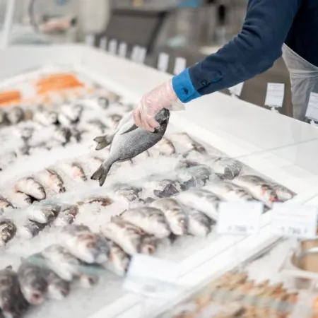 Fishmonger lays out fish on an ice counter in a supermarket. View from above on a counter with various seafood