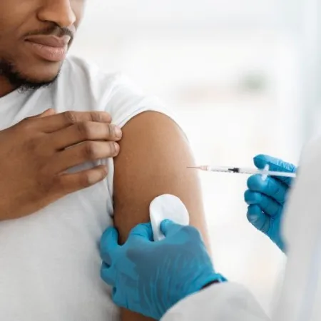 A medical professional administers a Covid vaccine to a Black man