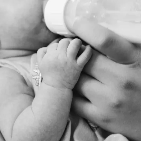 An infant drinking from a bottle in black and white