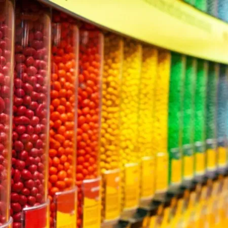 Colorful assortment of round candy drops in clear plastic containers arranged in a row.