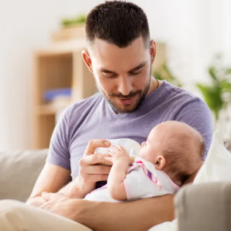 man bottle feeding a baby