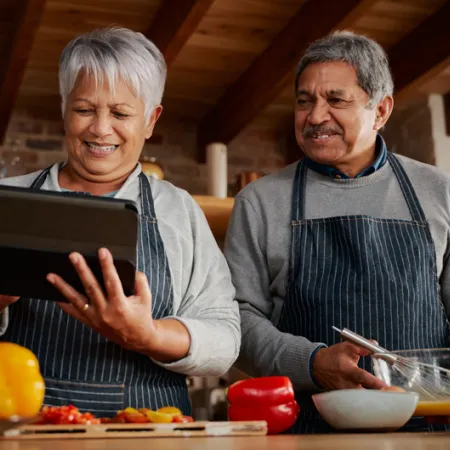 couple looking at an iPad and cooking in the kitchen