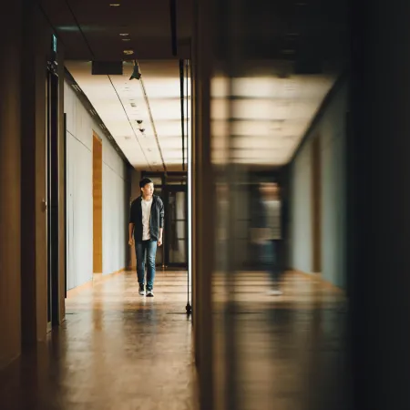 An adolescent boy walking alone down a school hallway