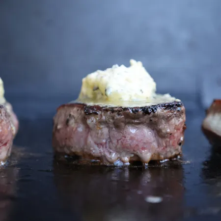 Eye fillet steaks on a grill topped with garlic butter