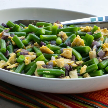 white bowl with green beans, egg and chopped onion