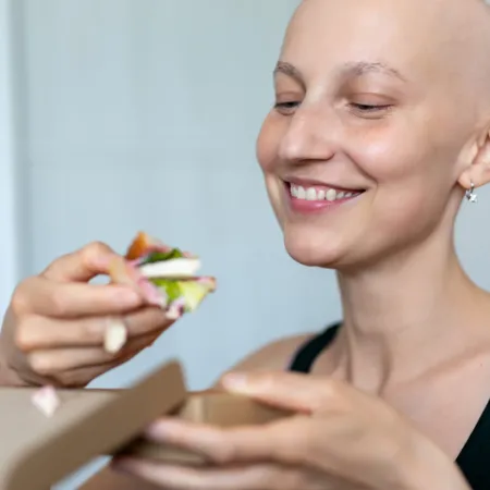 bald woman eating a salad with tofu in it