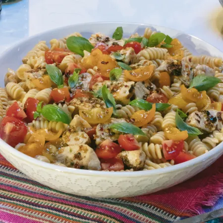 white bowl filled with tomato and chicken pasta salad