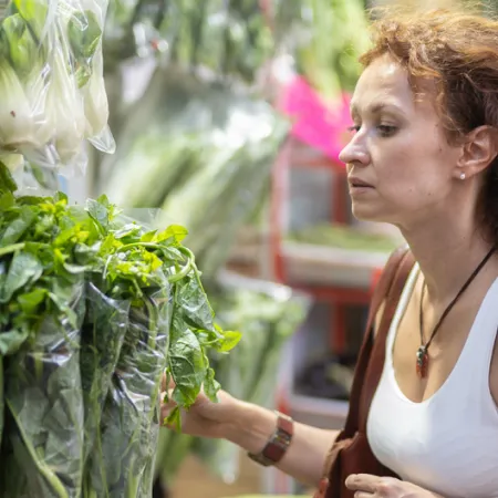 woman choosing a bunch of leafy greens in grocery store